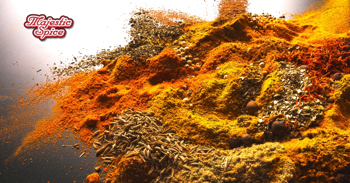 In this picture, we can see different spices and seeds mixed with each other. It features a range of colorful spice piles, including bright orange turmeric, deep red paprika, and earthy green herbs, all artfully arranged on a reflective surface. The company's logo, "Majestic Spice," is prominently displayed in a decorative script at the top left corner, adding a touch of elegance to the overall presentation.