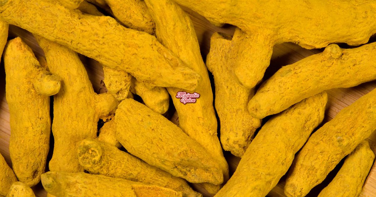 Close-up of dried whole turmeric roots with a vibrant golden-yellow color, showcasing their rough surface texture, with the Majestic Spice logo in the center.