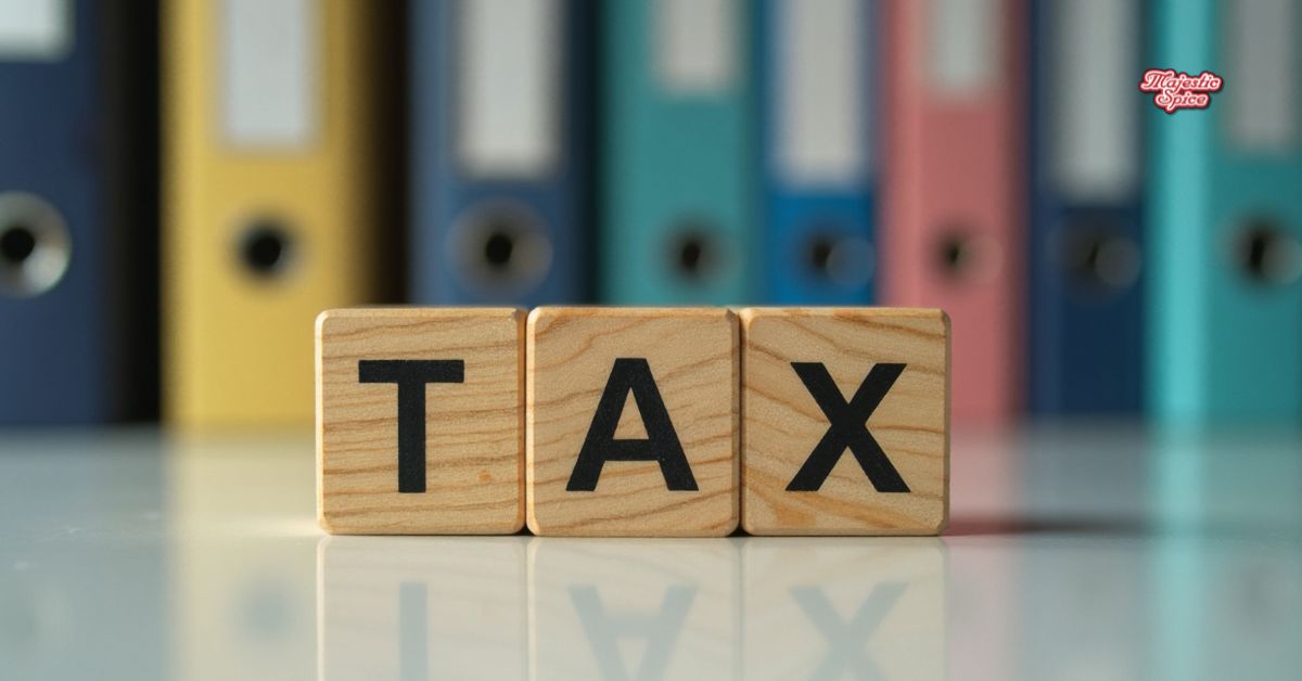 Wooden letter blocks spelling “TAX” on a reflective desk, with colorful office binders blurred in the background, symbolizing tariffs and taxation in a business or trade context.