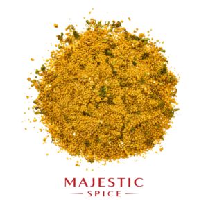 Mound of coarse golden adobo seasoning with visible green herb flakes and scattered spice particles, with the red Majestic Spice logo below.